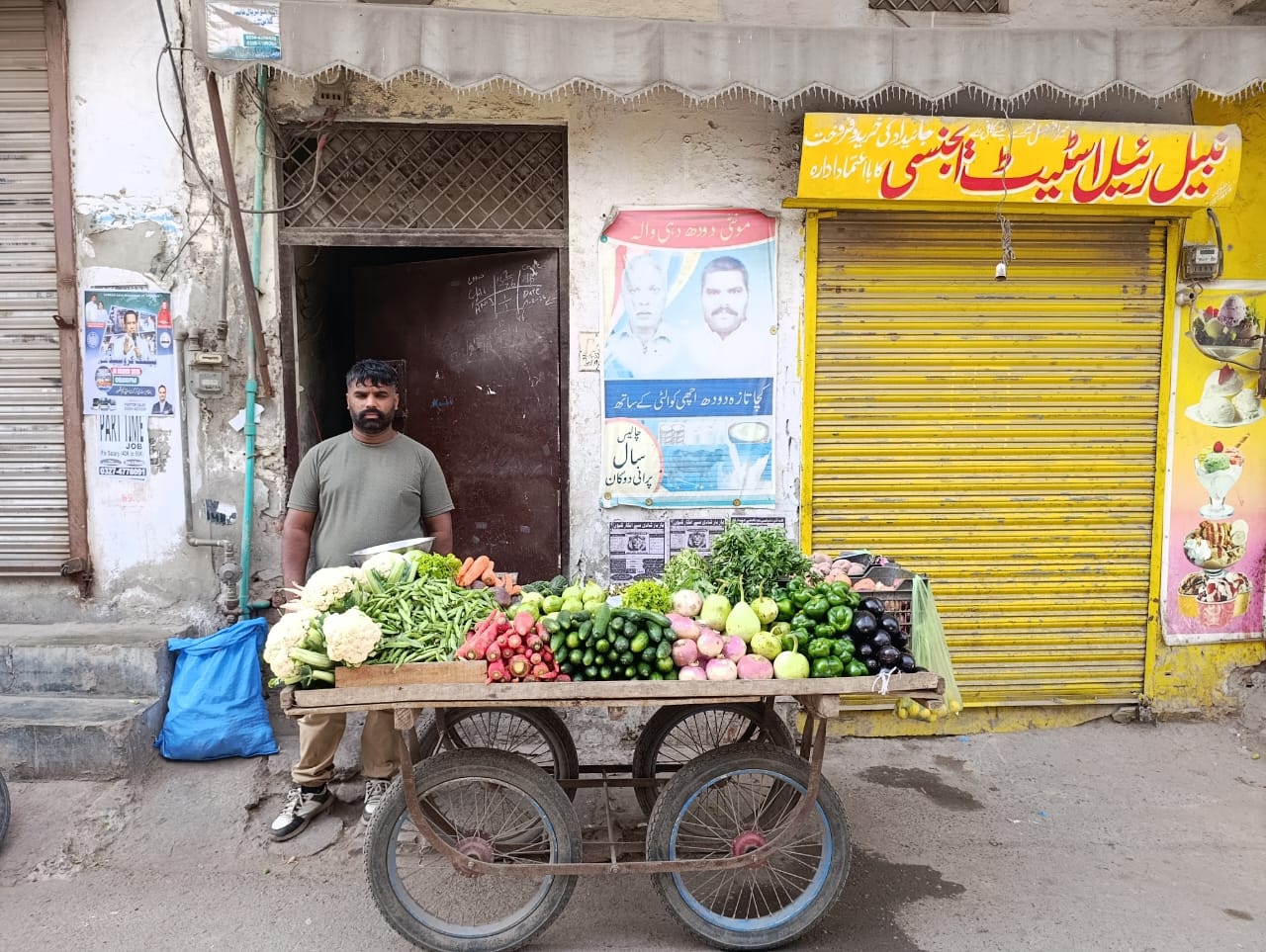 Sunil Masih stands beside his vegetable cart in front of his family’s former milk shop in Youhanabad, Lahore, Pakistan, on March 15, 2025. | Credit: Kamran Chaudhry
