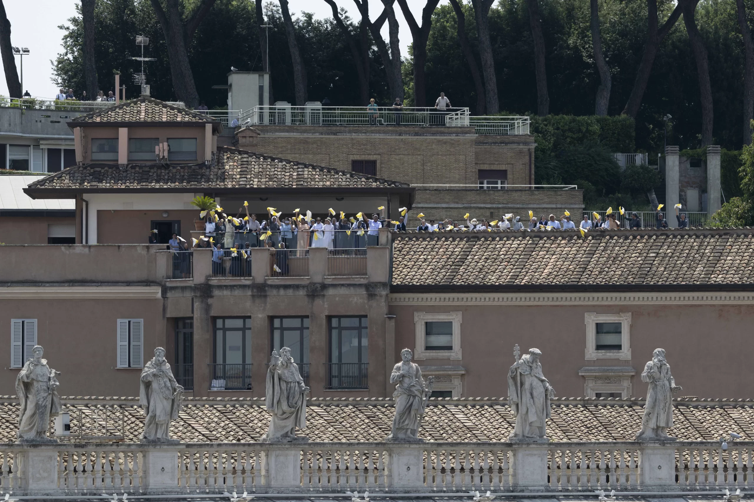 People wave from a nearby rooftop as Pope Francis delivers his Angelus address  on June 18, 2023. Vatican Media