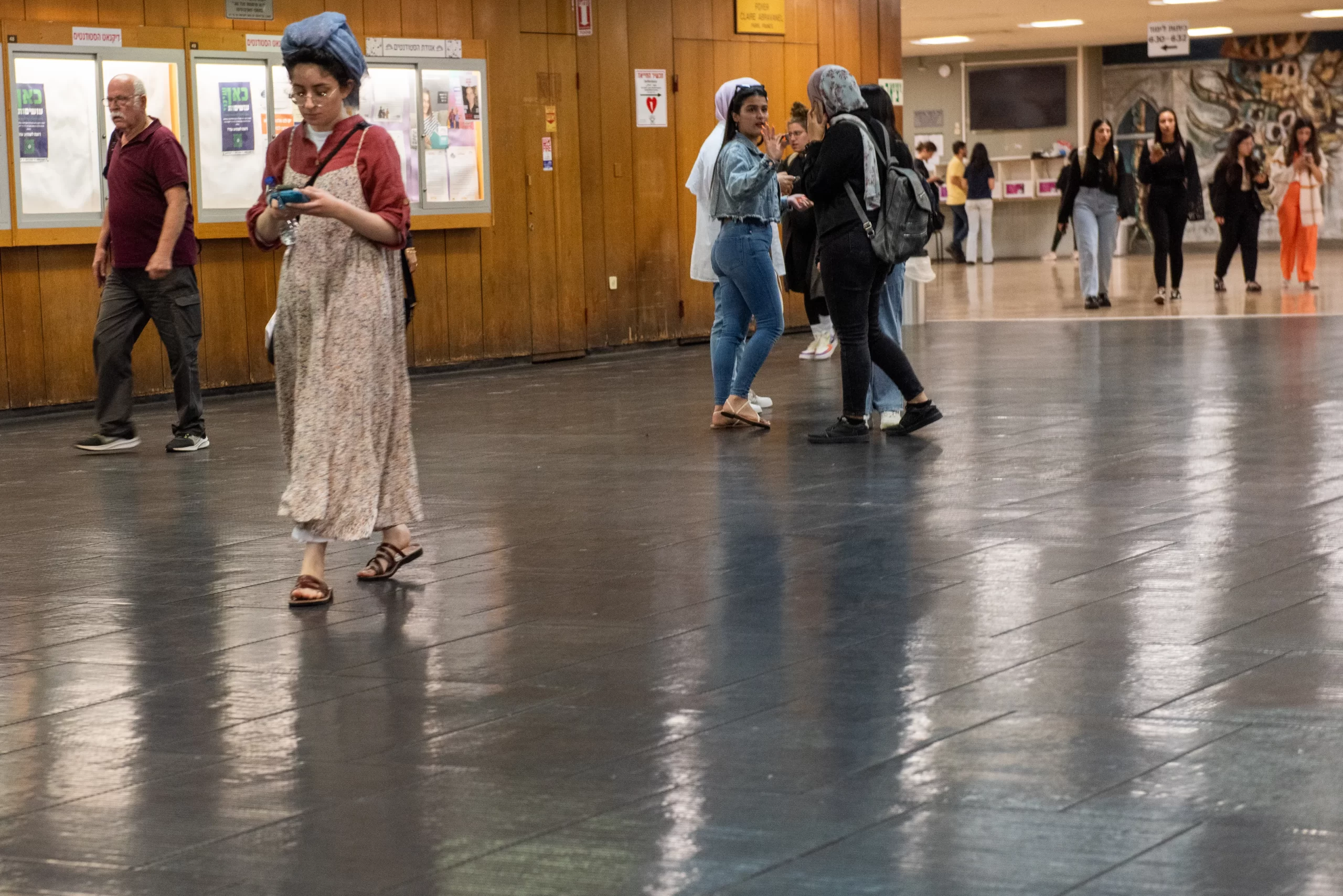 An Orthodox Jewish female student walks with Muslim students wearing headscarves visible in the background, alongside other students without specific religious attire in the corridors of the University of Haifa. In the campus classrooms, there are Jews, Muslims, Druze, and Christians comprising 15-20 different religious denominations. Credit: Marinella Bandini