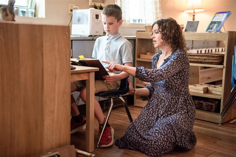 A Lower Elementary assistant at Christ the King Catholic Montessori school assists a student with research in spring 2023. Credit: Mike McCleary/University of Mary