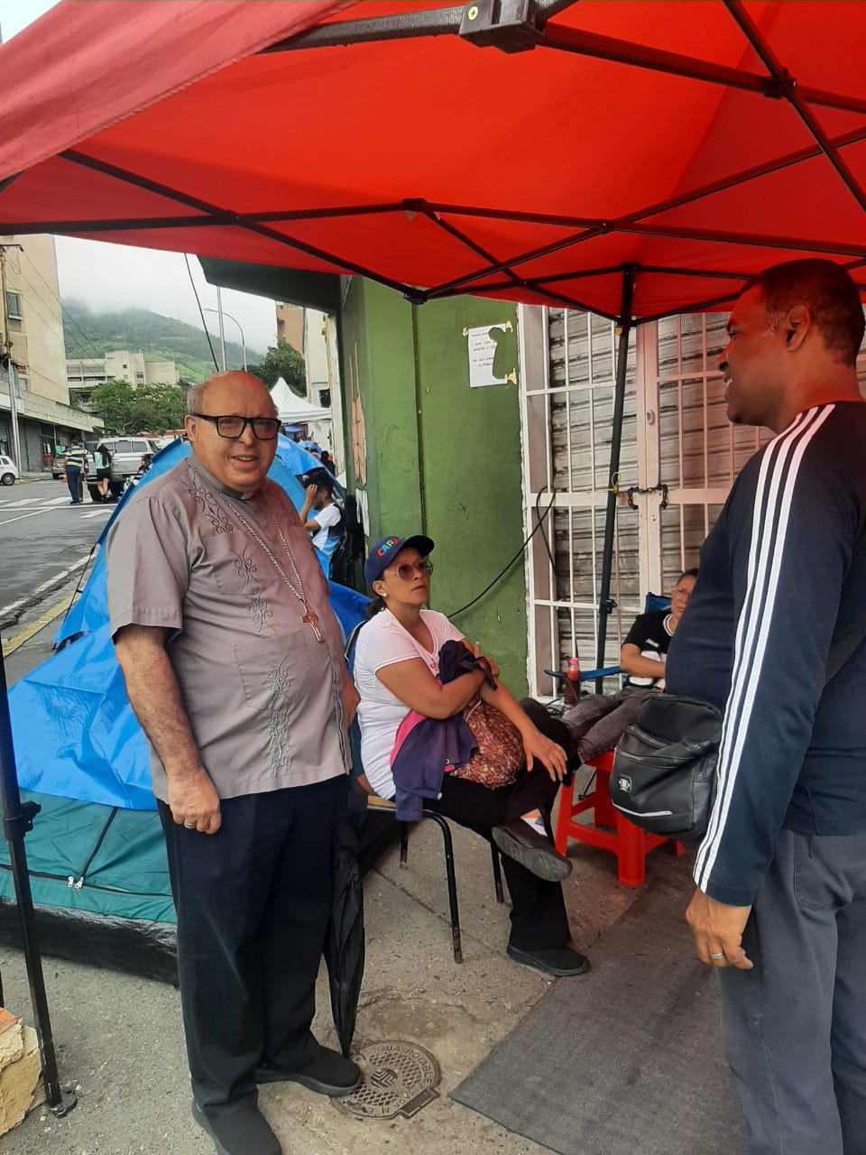 Carlos Márquez, auxiliary bishop of Caracas, left, with people affected by the June 24, 2026, earthquakes in Venezuela. | Credit: Photo courtesy of Bishop Carlos Márquez