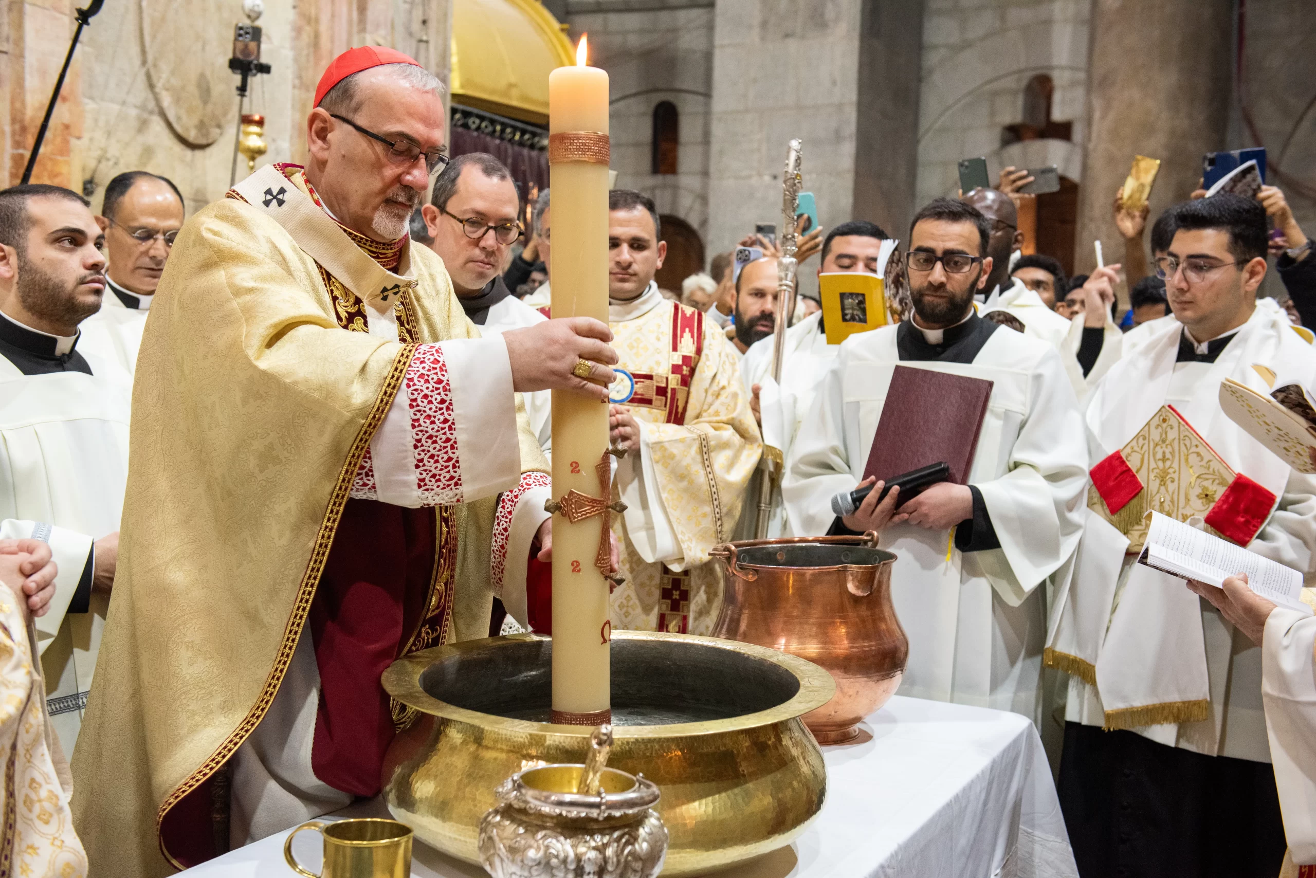 Cardinale Pierbattista Pizzaballa, the Latin patriarch of Jerusalem, dips the Easter candle into the water to bless it during the Easter Vigil, which was celebrated on the morning of Saturday, March 30, 2024, in the Basilica of the Holy Sepulcher in Jerusalem. The liturgy of this day includes the renewal of baptismal promises. On the north side of the edicule of the Holy Sepulchre, the patriarch blesses the water by immersing the Easter candle in a very evocative rite. Credit: Marinella Bandini