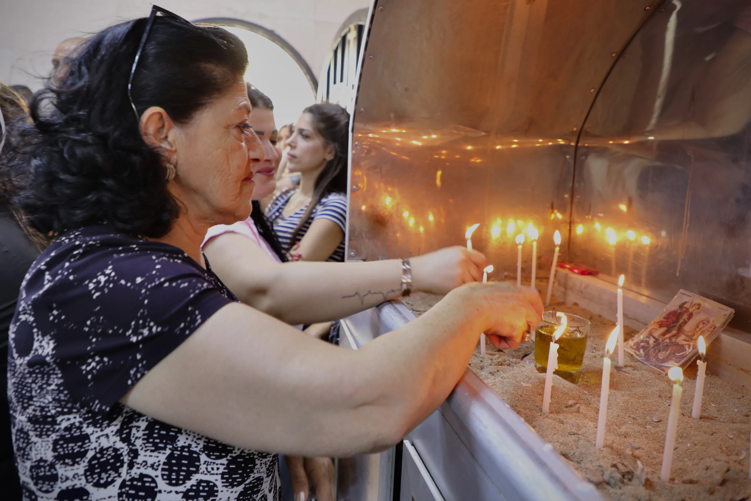 A woman lights a candle as the Syrian village of Ghassaniyeh gathers in prayer once again. | Credit: ACI MENA