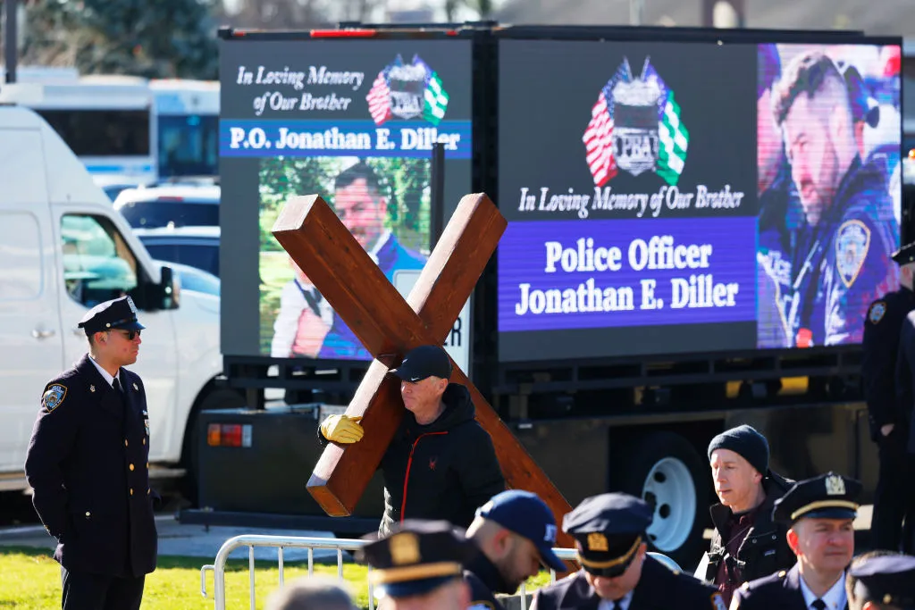 A man holds a cross outside the funeral of NYPD officer Jonathan Diller at St. Rose of Lima Catholic Church on Holy Saturday, March 30, 2024, in Massapequa, New York. Credit: Michael M. Santiago/Getty Images